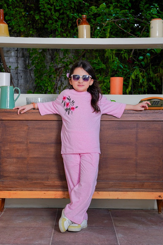Child in pink outfit with sunglasses standing in a kitchen setting