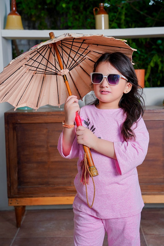 Child in pink outfit holding a traditional umbrella with a blurred indoor background
