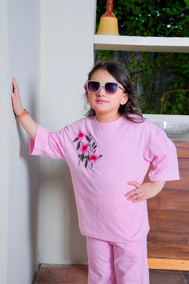 Child wearing a pink outfit with floral designs indoors.