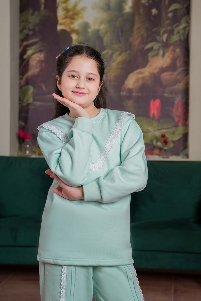 Young girl in a light green outfit posing in front of a colorful painting.