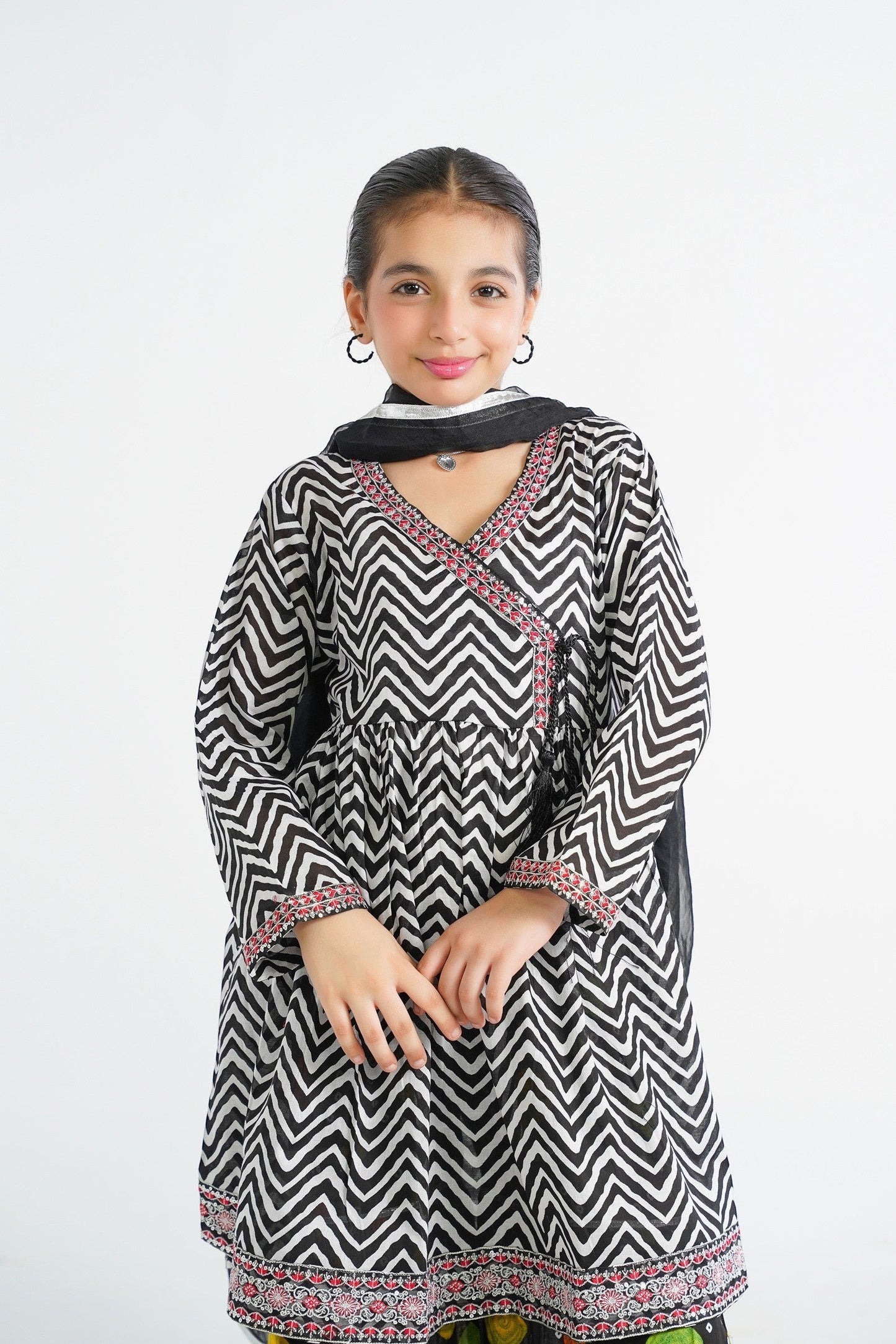 Lily black and white zigzag print kurta with red embroidery and tassels, paired with colorful tiered sharara and black dupatta.