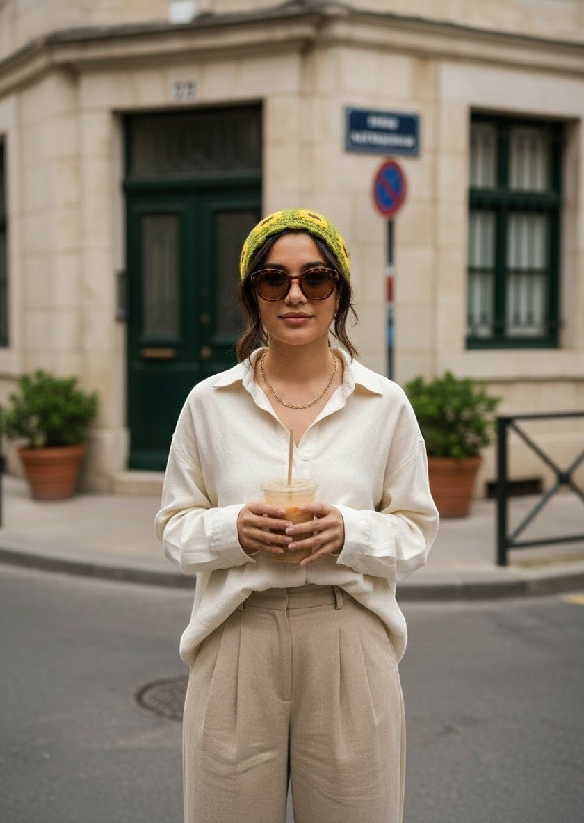 Lily crochet sunflower hair bandana in green and yellow worn by a woman with sunglasses on a city street.