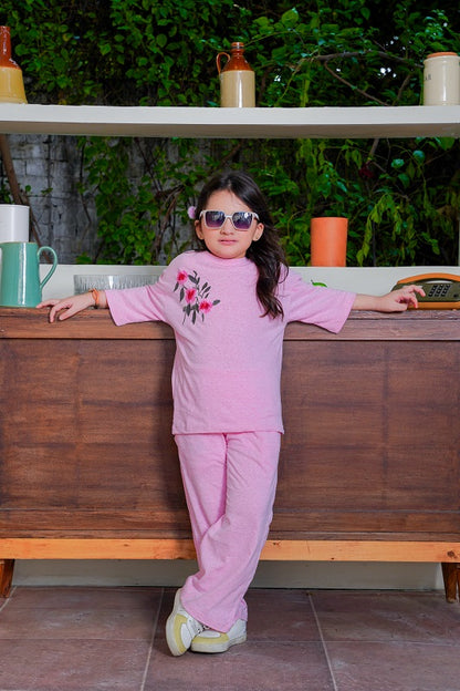 Child in pink outfit with sunglasses standing in a kitchen setting