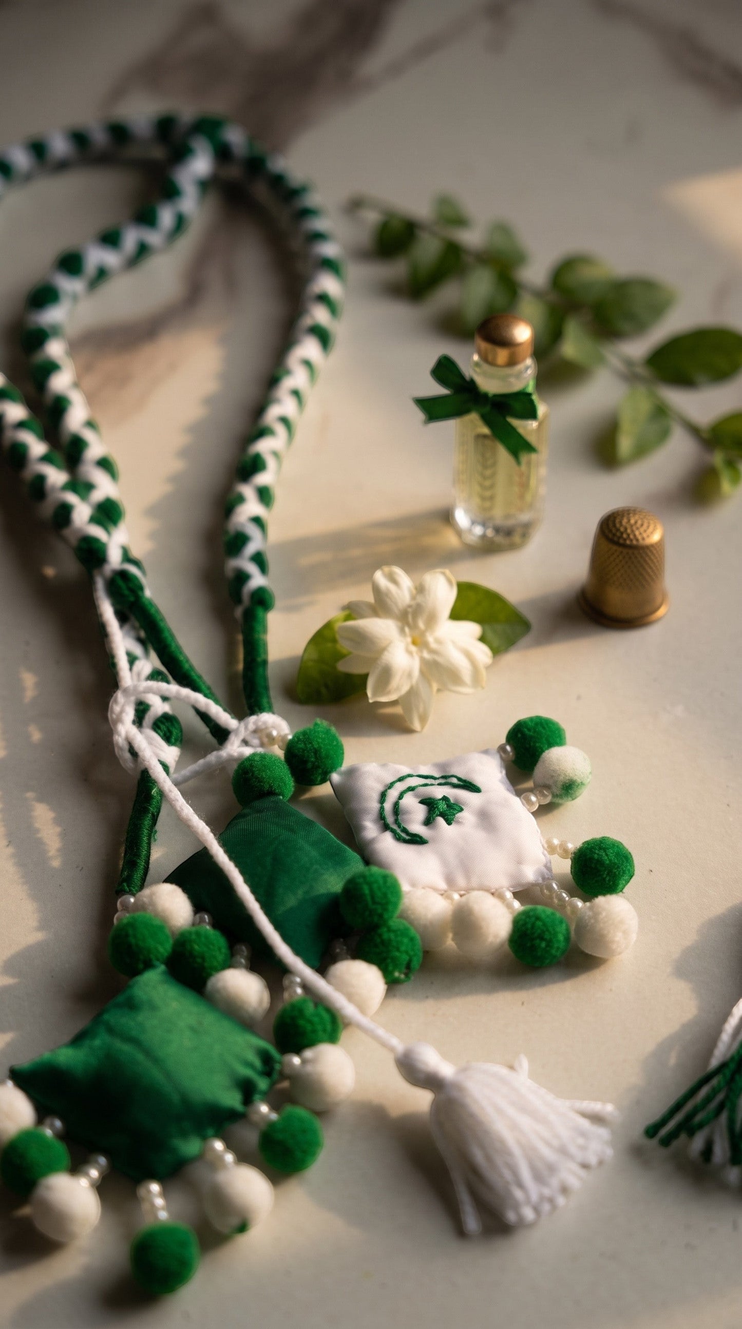 Lily 14 August special braided hair accessory in green and white with pom-poms and embroidered crescent and star.