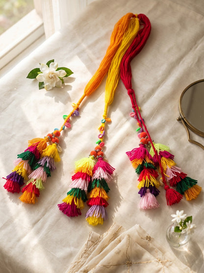 Lily Basanti Paranda hair accessory with vibrant multi-colored yarn tassels, pom-poms, and intricate beadwork.