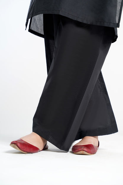 Lily black floral print kurti with pants, featuring flared sleeves and a relaxed fit. Paired with red flats.