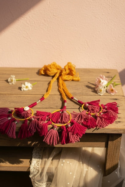 Lily bohemian tassel hair accessory with magenta and mustard yellow threads, shell accents, and yellow bow.