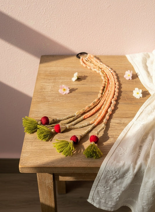 Lily braided hair accessory with peach yarn, red beads, and lime green tassels. Bohemian style.