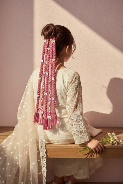 Lily braided hair extensions in pink and white yarn with butterfly charms and bows, attached to a girl's bun.