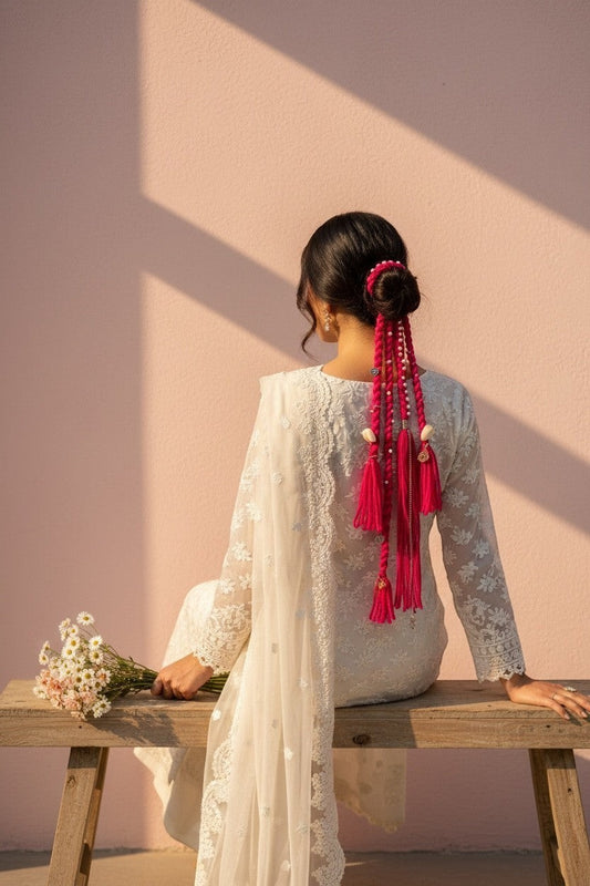 Lily braided fuchsia yarn hair accessory with pearls and tassels attached to a bun.