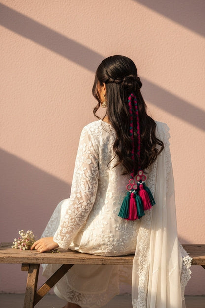 Lily braided hair accessory with teal and fuchsia tassels and mirrored charms, styled in a woman's dark hair.