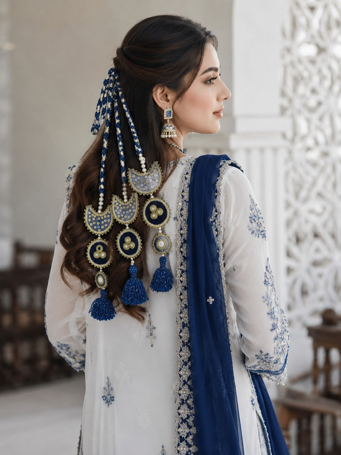 Lily Chaand Rani Paranda featuring navy blue and cream crescent motifs with mirror work and tassels in a woman's hair