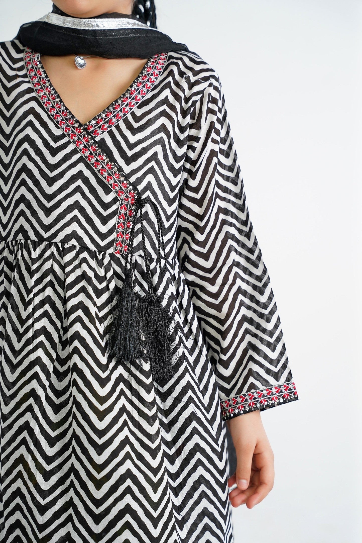 Lily black and white chevron print kurta with red embroidery and black tassels, V-neckline, paired with colorful tiered sharara and dupatta.
