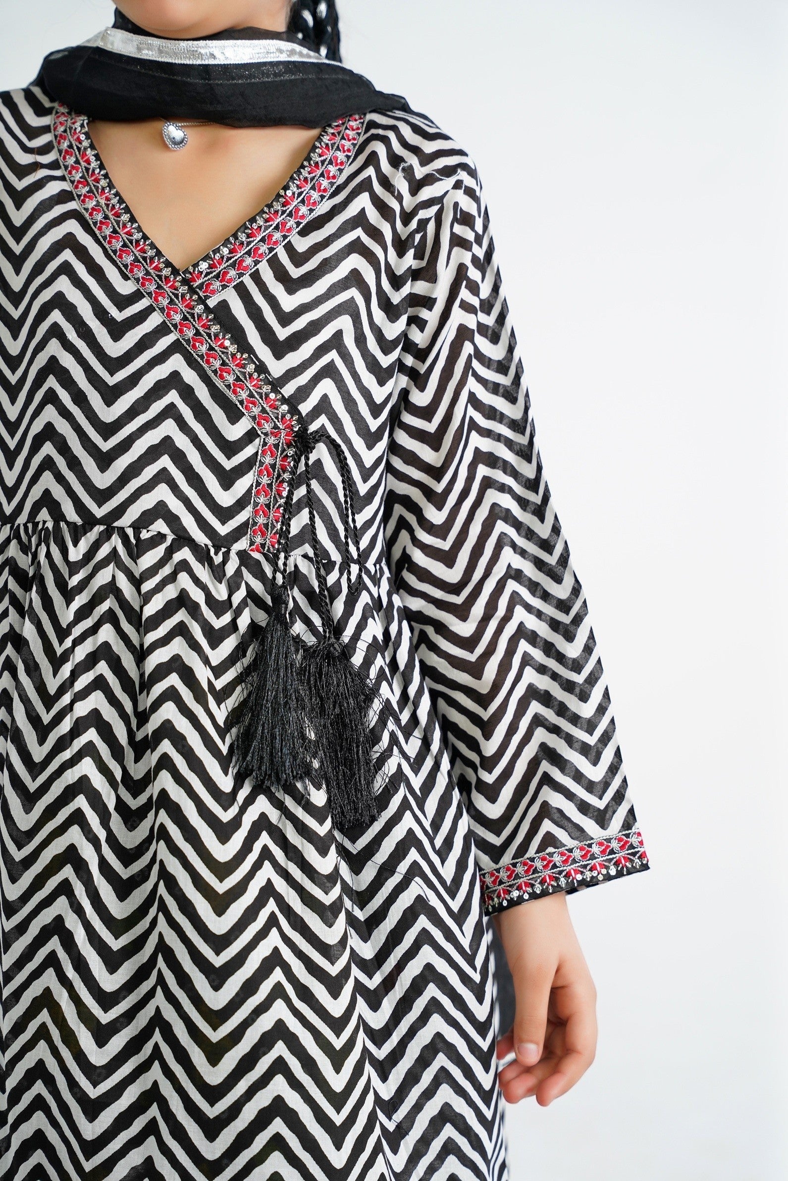Lily black and white chevron print kurta with red embroidery and black tassels, V-neckline, paired with colorful tiered sharara and dupatta.