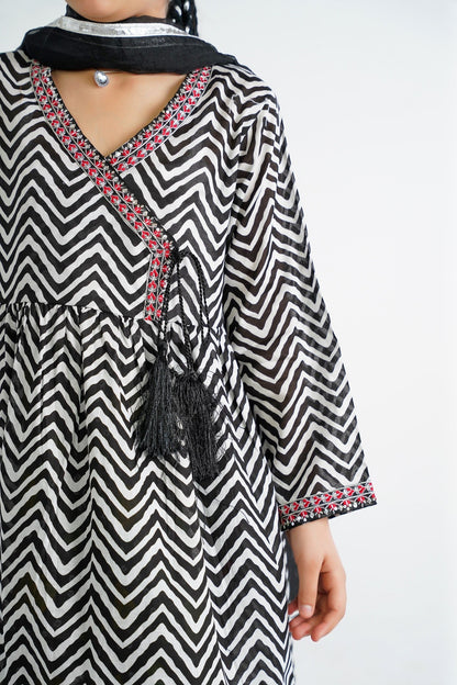 Lily black and white chevron print kurta with red embroidery and black tassels, V-neckline, paired with colorful tiered sharara and dupatta.
