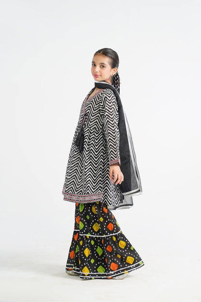 Lily black and white zigzag print kurta with red embroidery and tassels, paired with colorful tiered sharara and black dupatta.