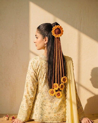 Lily crocheted sunflower hair accessory with dangling strands and floral accents in yellow and brown.