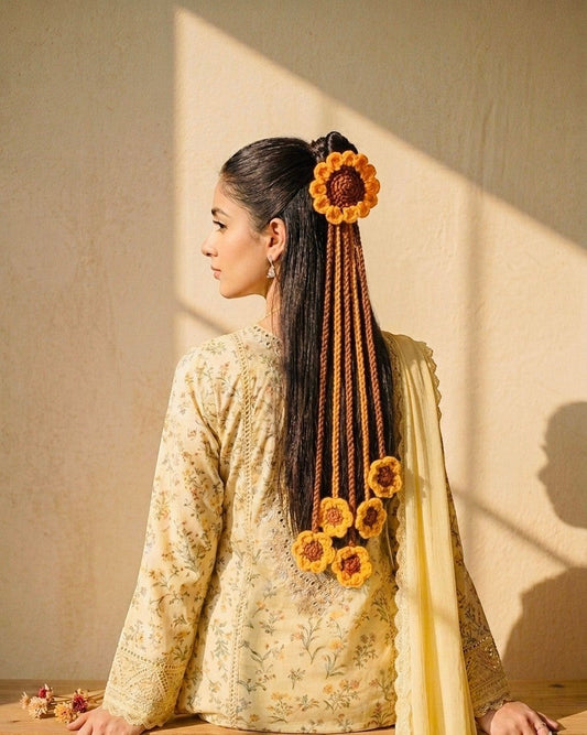 Lily crocheted sunflower hair accessory with dangling strands and floral accents in yellow and brown.