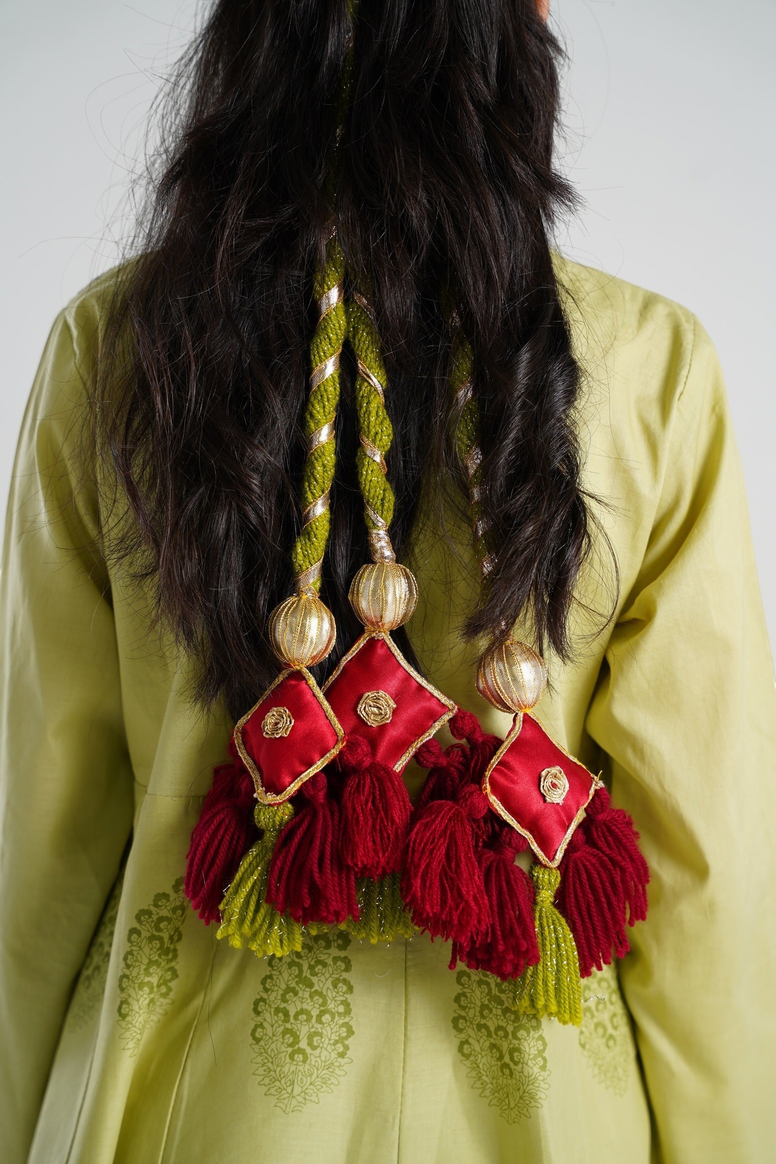 Lily decorative tassels with braided gold and green cord, maroon fringe, and red satin square accents with gold embroidery.