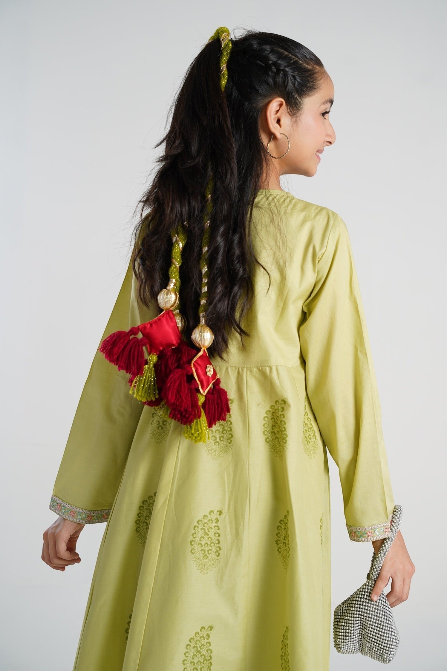 Lily Dil Ruba decorative tassels with maroon fringe, red satin square, and gold embroidery, attached to a girl's braided hair.