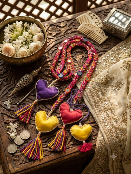 Lily Dilruba Paranda hair accessory with braided pink, purple, and yellow cords, mirror accents, and plush heart charms.