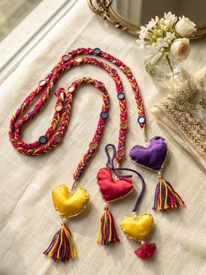 Lily Dilruba Paranda hair accessory with braided pink, purple, and yellow cord, mirror accents, and satin hearts.