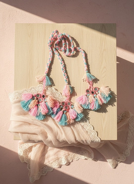 Lily embellished tassel necklace with mirror accents in pink, blue, and peach yarn. Braided cord and tassels add bohemian flair.