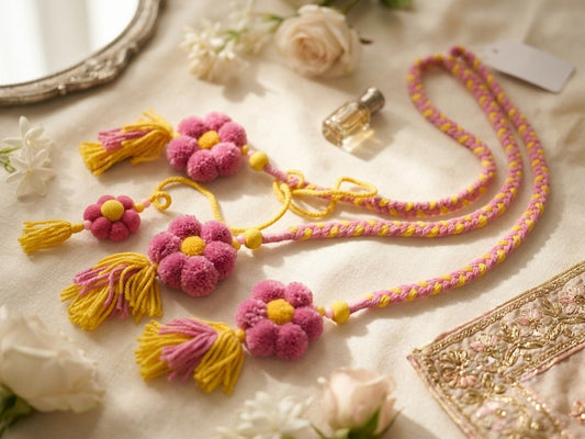 Lily handcrafted floral pom pom paranda in pink and yellow with braided cords, tassels, and wooden bead accents.