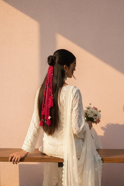 Lily fuchsia braided yarn hair accessory with pearls and tassels, styled in a half-up bun.