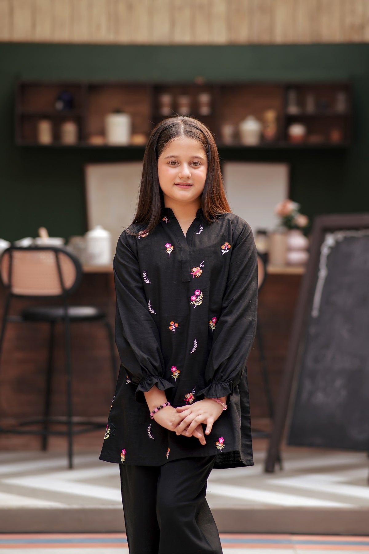 Lily girls black tunic and trouser set with vibrant floral embroidery, V-neckline, and ruffled long sleeves.