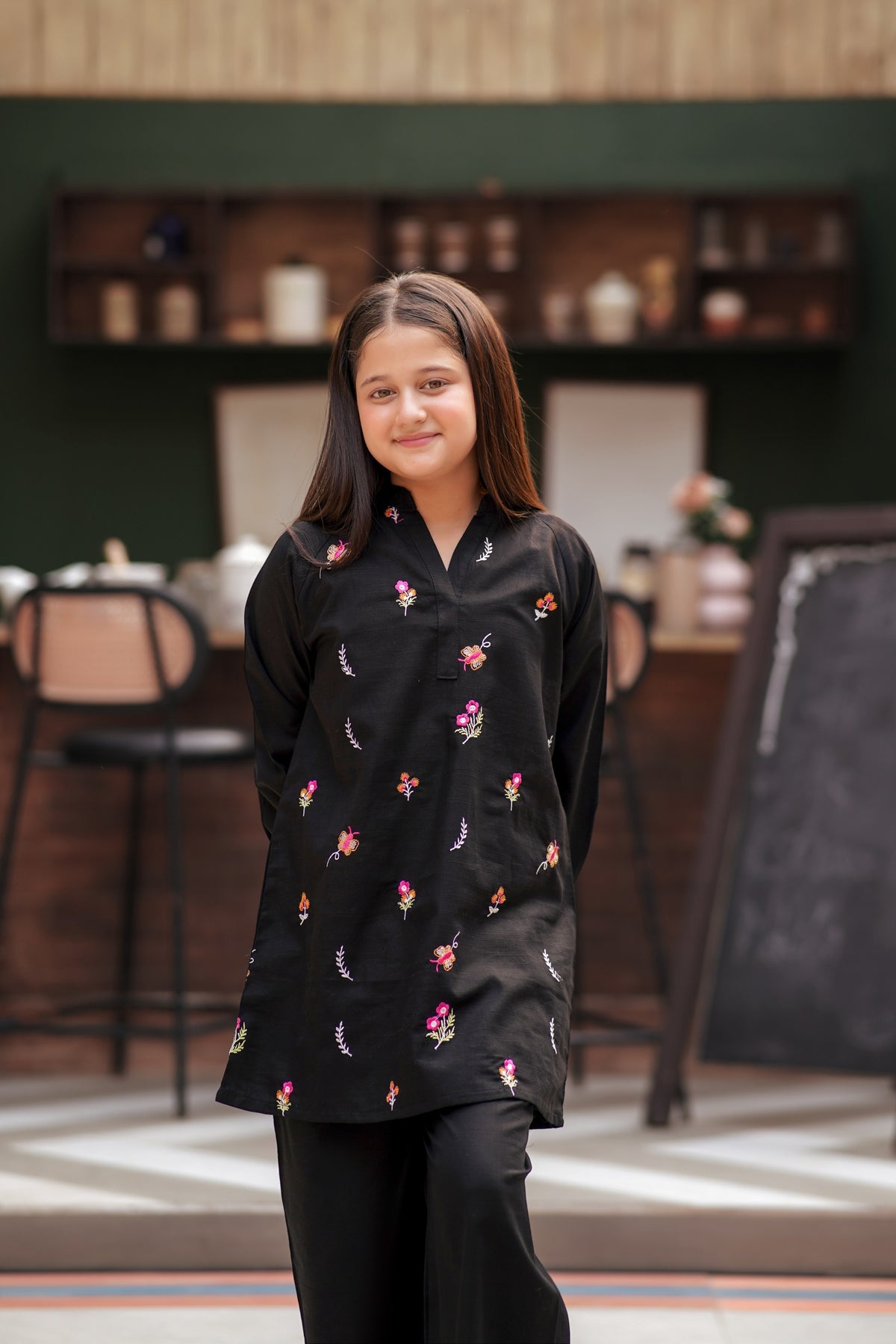 Lily girls black tunic set with multi-colored floral embroidery, V-neckline, and long sleeves in a studio setting.