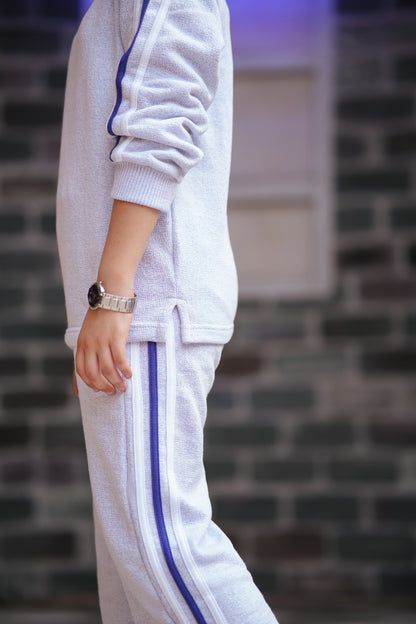 Lily girls white textured two-piece tracksuit with purple side stripes and ribbed cuffs, side view.