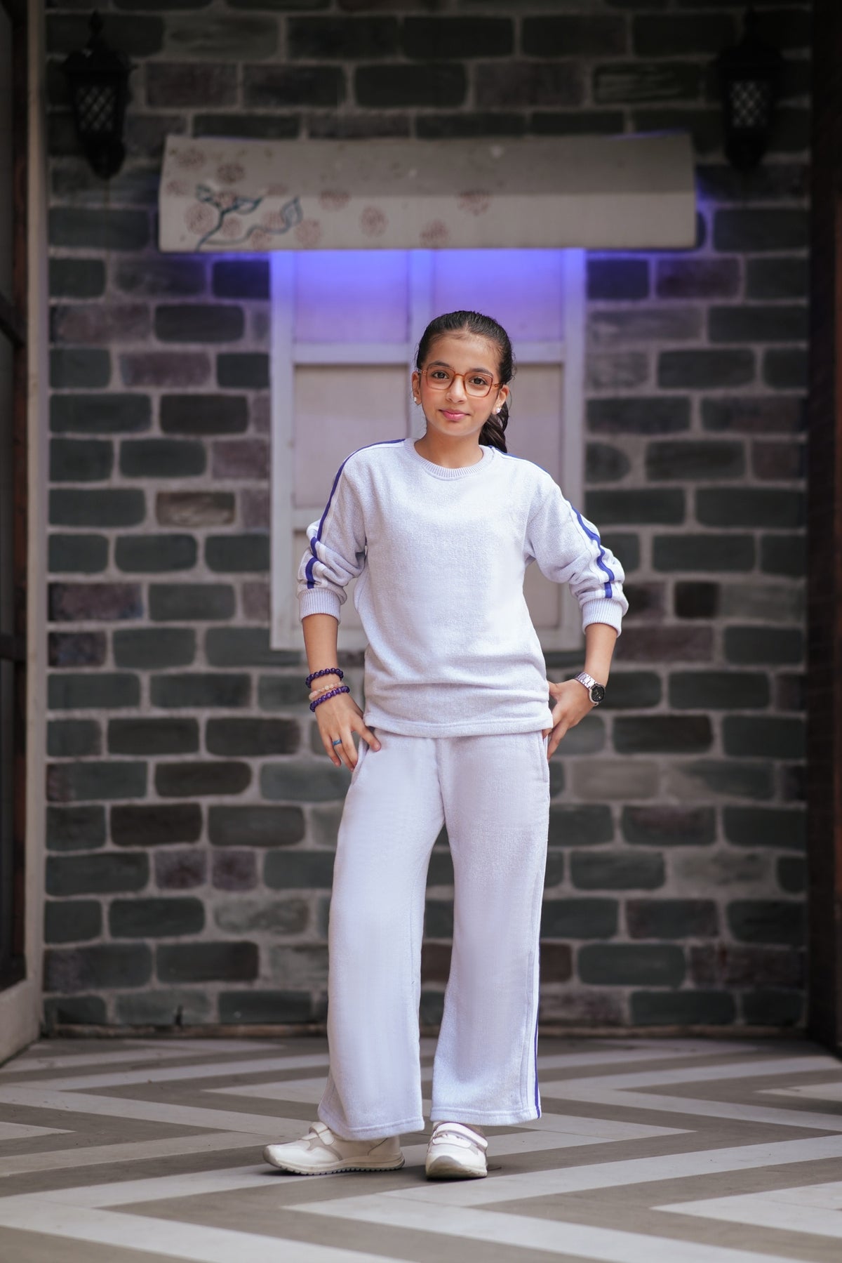 Lily girls white two-piece tracksuit with purple side stripes, featuring a relaxed fit top and matching trousers.