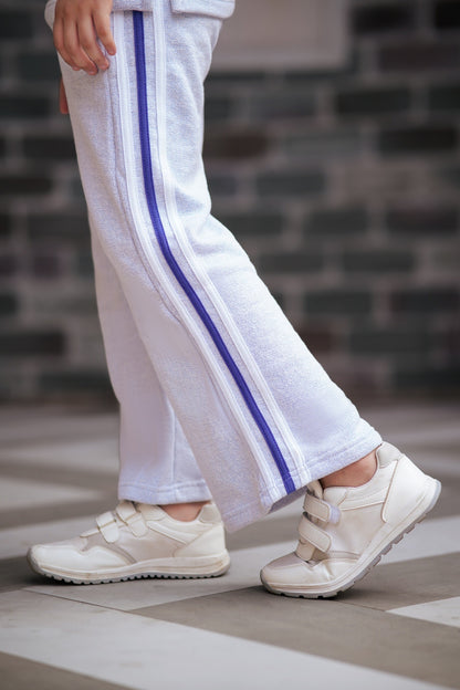 Lily girls white textured tracksuit pants with purple side stripes worn with white sneakers