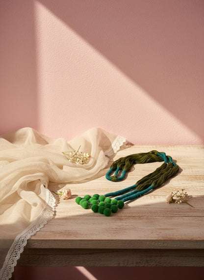 Lily handcrafted necklace with green pom-poms and braided teal & green cord. Artisanal ethnic jewelry.