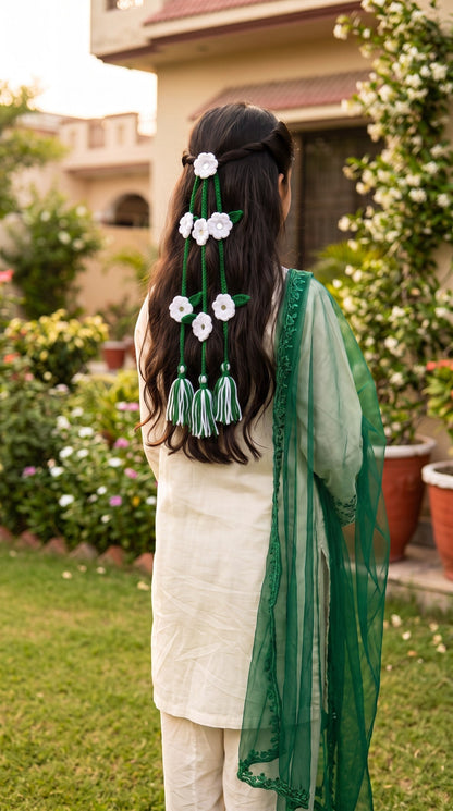 Lily green and white crocheted flower hair braids with mirror centers and tassels worn by a woman in a garden