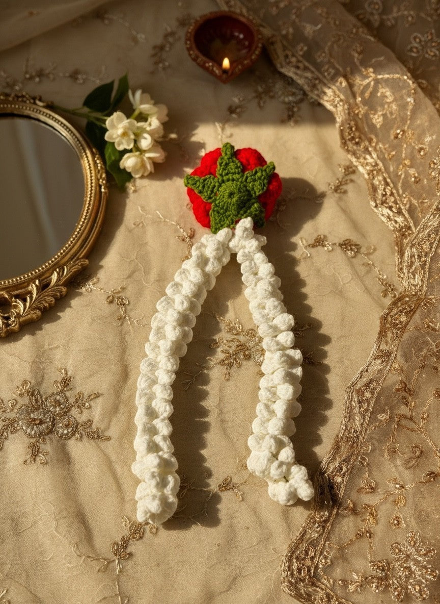 Lily handmade crochet hair accessory featuring a vibrant red rose and cream jasmine strands on a gold fabric background.