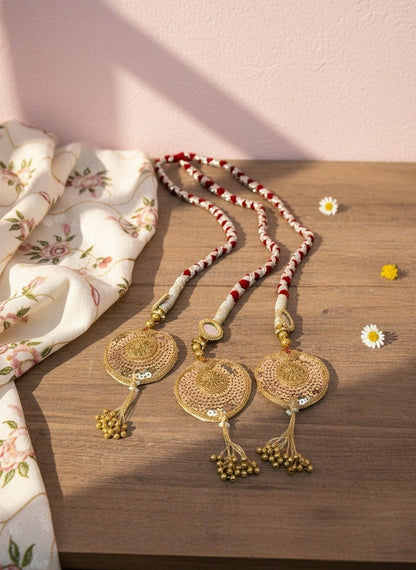 Lily traditional Indian bridal hair accessory with red and white braided cord, gold sequin pendants, and gold bead tassels.