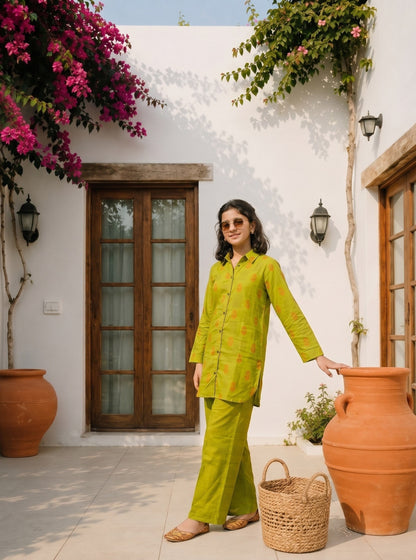 Lily lime green long sleeve shirt and wide leg trouser set with orange pattern worn by a woman on a patio.