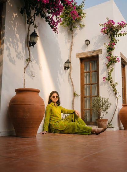 Lily lime green long sleeve shirt and wide leg trouser set with orange pattern worn by a woman on a terracotta patio