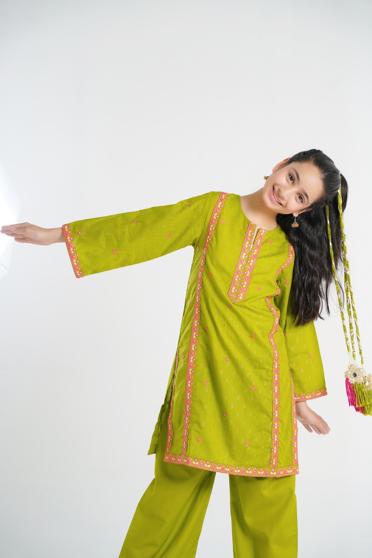 Lily lime green cotton kurta and trouser set with pink embroidery on neckline, sleeves, and hem. A young girl models the outfit.