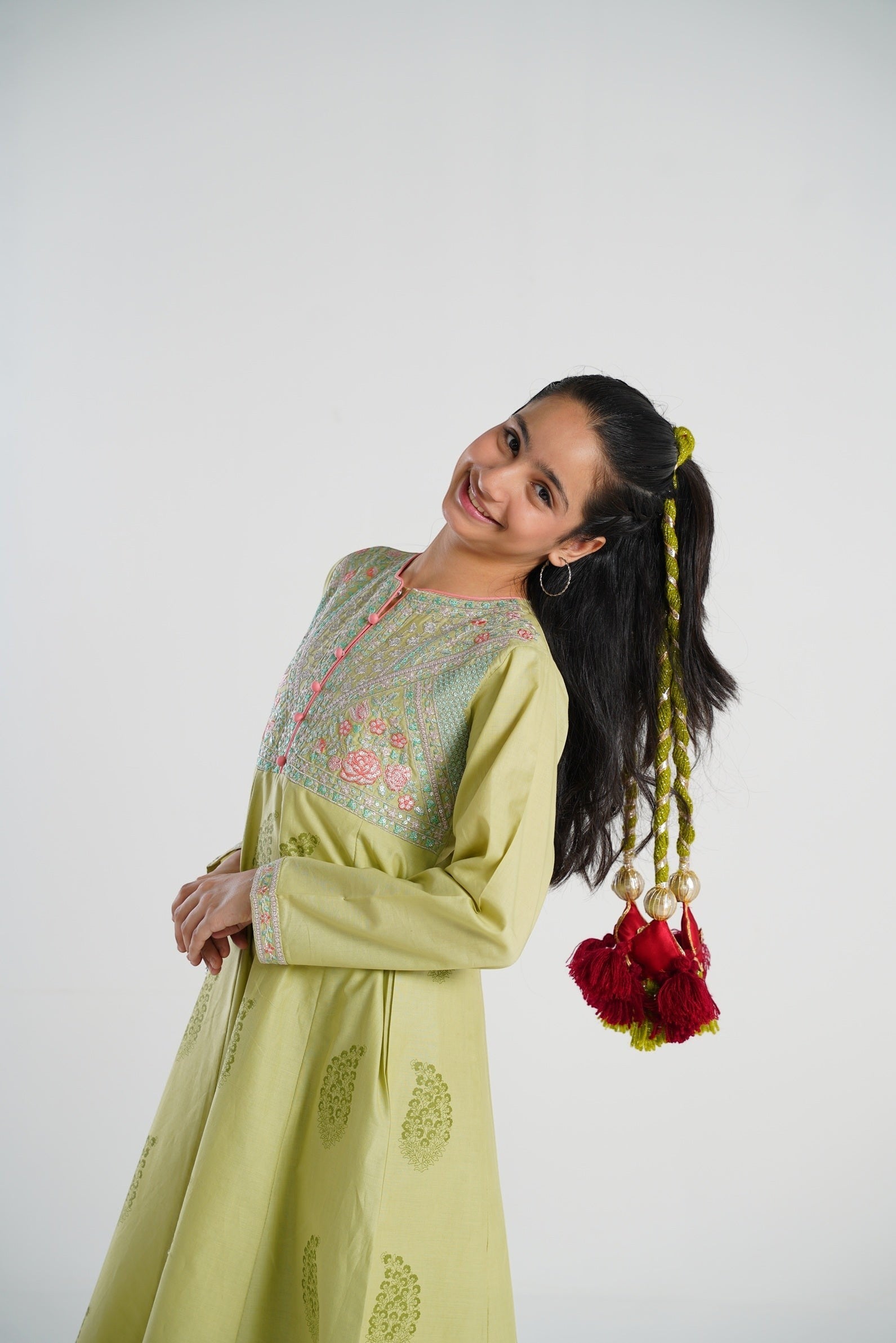 Lily girl in light green embroidered kurta with maroon tassels and gold embroidery on hair tie.