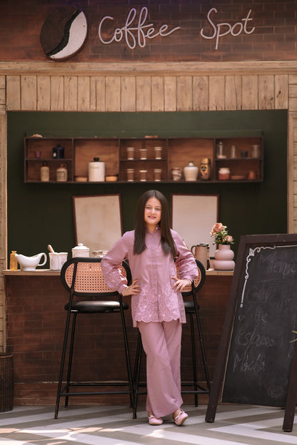 Lily girl wearing a mauve long-sleeved button-down shirt with floral embroidery and matching trousers in a cafe setting