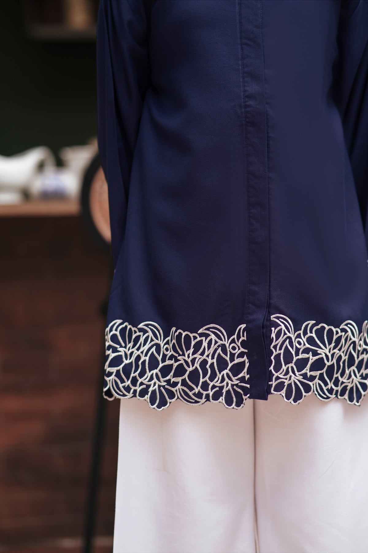 Lily navy blue long sleeve button-down tunic with intricate white floral embroidery on the scalloped hemline