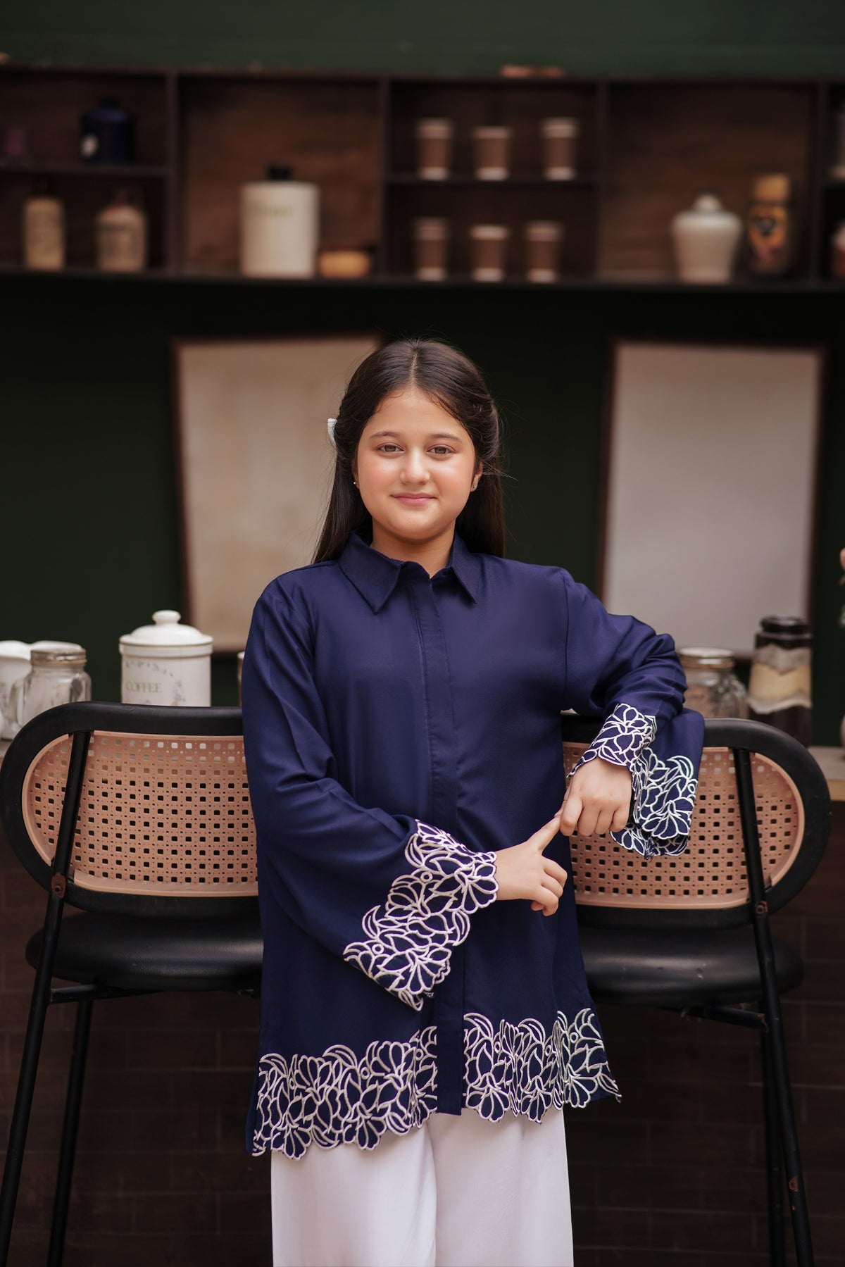 Lily navy blue long sleeve button-down tunic with white floral embroidery on cuffs and scalloped hem worn by a girl