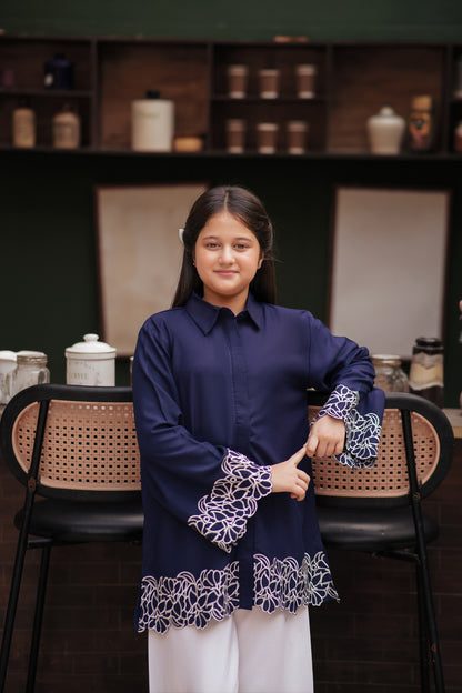 Lily navy blue long sleeve button-down tunic with white floral embroidery on cuffs and scalloped hem worn by a girl