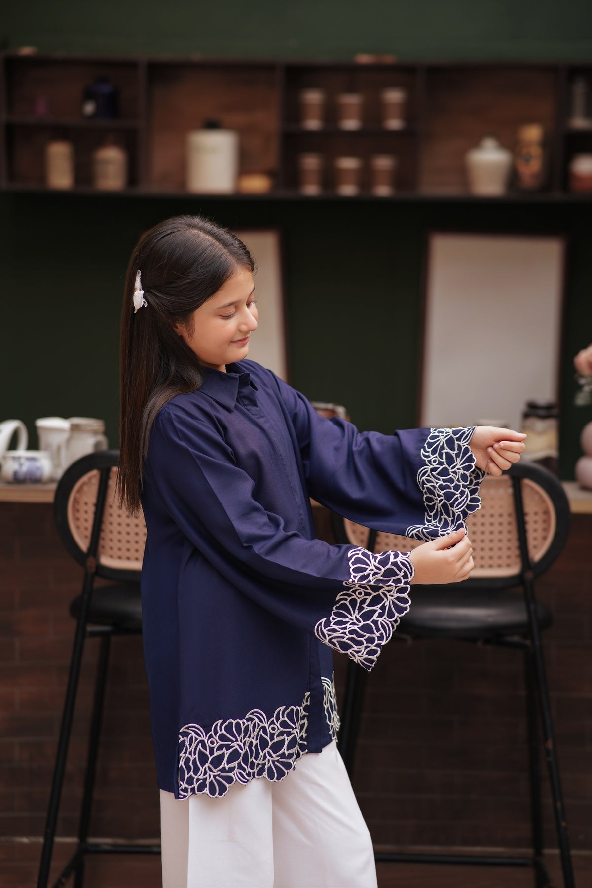 Lily navy blue long sleeve button down tunic with white floral embroidery on wide cuffs and scalloped hem on a girl