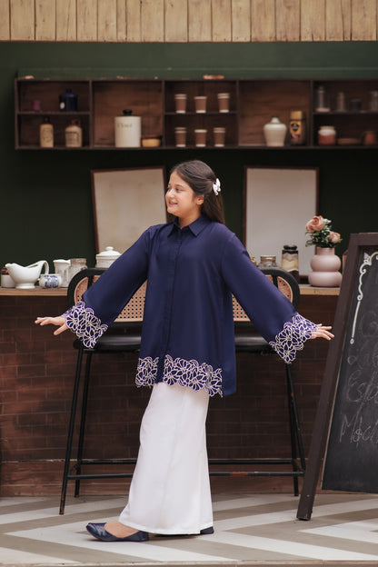 Lily navy blue long sleeve button-down tunic with white floral embroidery on cuffs and scalloped hem worn by a girl