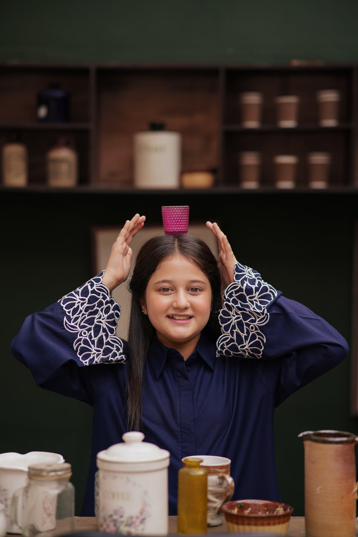 Lily navy blue long sleeve button down tunic with white floral embroidery on cuffs, worn by a smiling young girl.