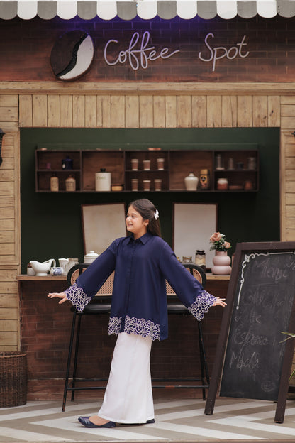 Lily girl wearing a navy blue long sleeve button-down tunic with white floral embroidery on cuffs and scalloped hem